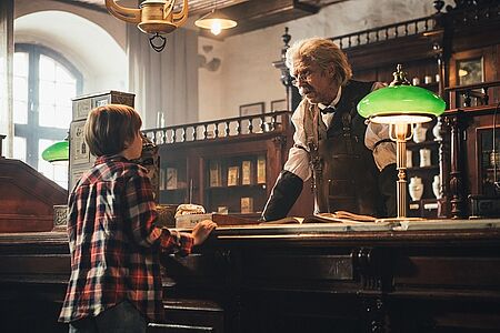Winski Junge am Schalter eines alten Apothekers, der mit einem alten Mann spricht
